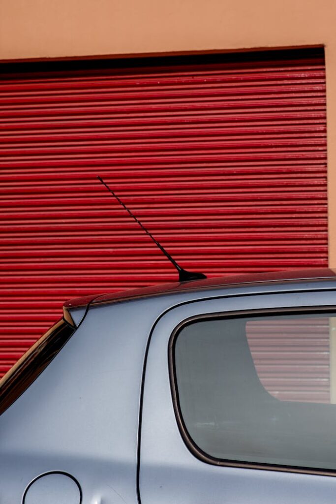 A sleek car parked in front of a vibrant red garage door, creating a striking contrast.